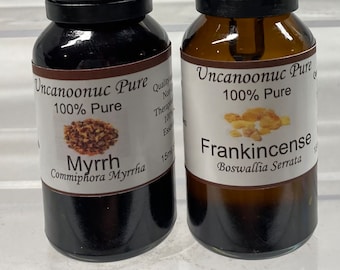 May include: Two glass dropper bottles of essential oils. One is dark with a label that reads "Myrrh Commiphora Myrrha." The other is amber with a label that reads "Frankincense Boswallia Serrata." Both are labeled "Uncanoonuc Pure 100% Pure."