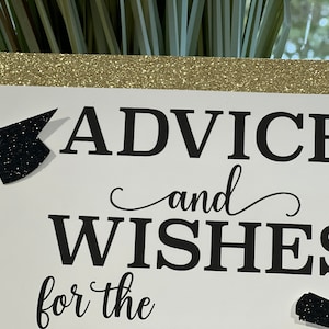 Peut inclure: Une carte blanche avec une bordure dor&eacute;e scintillante et du texte noir qui dit "Conseils et v&oelig;ux pour le". Il y a un chapeau de graduation noir et un dipl&ocirc;me noir sur la carte.