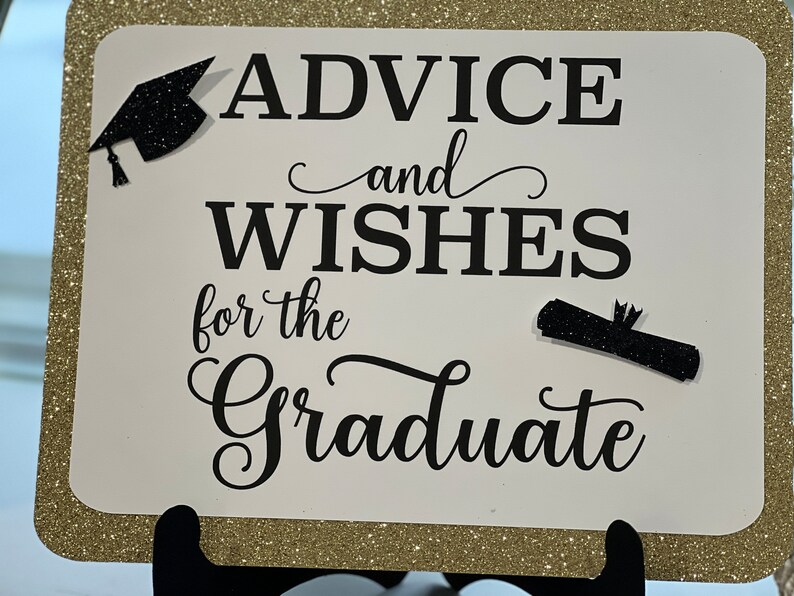 Peut inclure: Une pancarte blanche avec une bordure dor&eacute;e scintillante. La pancarte dit "Conseils et v&oelig;ux pour le dipl&ocirc;m&eacute;" avec une silhouette noire de chapeau de graduation et de dipl&ocirc;me.