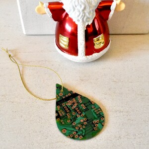 Puede incluir: Adorno de Navidad de Santa Claus rojo y dorado con barba blanca y adorno de placa de circuito verde con cuerda dorada.