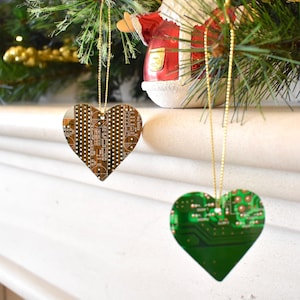 Może przedstawiać: Dwie choinkowe ozdoby w kształcie serca wykonane z płytek obwodów drukowanych. Jedna ozdoba jest zielona, a druga brązowa.