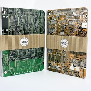 May include: Two notebooks with covers made from recycled circuit boards. The covers are green and brown with a black and white label that reads "Made from Circuit Boards Recycled".