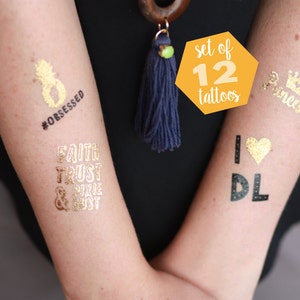 May include: A set of 12 gold temporary tattoos with various designs, including a pineapple, a crown, a heart, and text that says "#obsessed", "Faith Trust & Pixie Dust", and "I love DL".