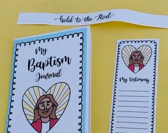 May include: A white journal with a blue border and a spiral binding. The cover features a heart with a yellow and white sunburst design and a cartoon image of Jesus. The text "My Baptism Journal" is printed in black. A white bookmark with a black border and a heart with a yellow and white sunburst design and a cartoon image of Jesus. The text "My Testimony" is printed in black. A white banner with black text that reads "hold to the Rod".