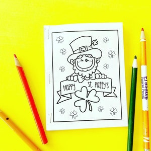 May include: A black and white colouring page featuring a leprechaun wearing a hat and holding a banner that says "Happy St. Patty's".