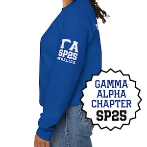 May include: Royal blue sweatshirt with white text on the sleeve and a graphic on the front. The sleeve text reads "ΓΑ SP25 46 R.E.L.I.C.S." The front graphic says "GAMMA ALPHA CHAPTER SP25" in a black and white design.