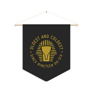 May include: Black pennant banner with a gold circle graphic that reads "Oldest and Coldest. Since Nineteen Oh-Six."  The graphic features a stylized pharaoh's head.