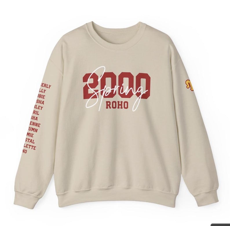 May include: A beige sweatshirt with a red "2000 Spring ROHO" graphic on the front. The sweatshirt has long sleeves and a crew neck.