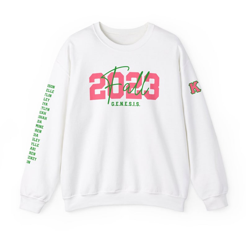 May include: White sweatshirt with a pink and green 'Fall 2023' graphic on the front and a green 'K' on the left sleeve. The text 'G.E.N.E.S.I.S.' is printed below the graphic.