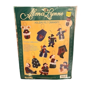 May include: A sealed package of Alma Lynne "Holiday Felt Ornaments" featuring a "Snowmen Celebration" design. The kit includes 12 felt appliqué ornaments, stamped felts, cotton embroidery floss, buttons, jute, needle, and instructions. Each ornament is approximately 4.5 inches (11 cm) high.