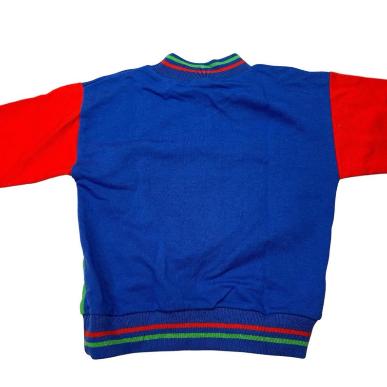 May include: A blue sweatshirt with red sleeves. The collar and hem feature green and red stripes. This vintage-style top is a colorful addition to any wardrobe.