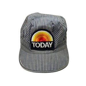 May include: A blue and white striped cap with a curved brim. The cap features a patch with a sunrise design in yellow, orange, and red, and the word "TODAY" in white letters.