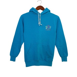 May include: A blue hooded sweatshirt with a white button closure and a small embroidered logo on the front. The logo features a colorful design with the text "Laguna Beach".