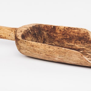 Puede incluir: Una pala de madera con un mango largo. La pala est&aacute; hecha de madera marr&oacute;n claro y tiene un aspecto desgastado y r&uacute;stico.
