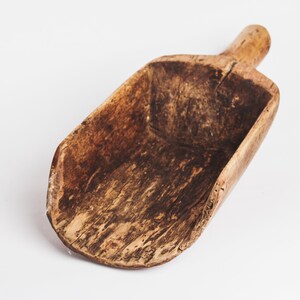Puede incluir: Una pala de madera con un acabado marr&oacute;n desgastado. La pala est&aacute; hecha de una sola pieza de madera y tiene un mango en un extremo.