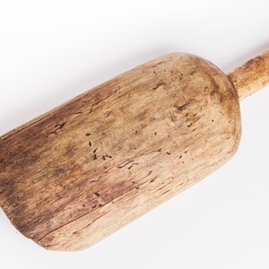 Puede incluir: Una pala de madera con un mango largo. La pala est&aacute; hecha de madera marr&oacute;n claro y tiene un aspecto desgastado y r&uacute;stico.