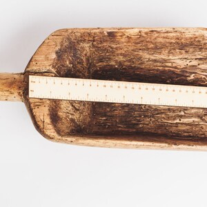 Puede incluir: Una pala de madera con un mango largo. La pala mide aproximadamente 30 cm de largo y tiene un aspecto r&uacute;stico y desgastado. Una regla se coloca junto a la pala para referencia de tama&ntilde;o.