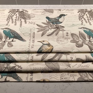 May include: A cream-colored fabric with a repeating pattern of blue birds, brown branches, and vintage-style postage stamps. The text on the stamps includes "VIA AIR MAIL", "N-5", "ORA MAY 27", and "2".