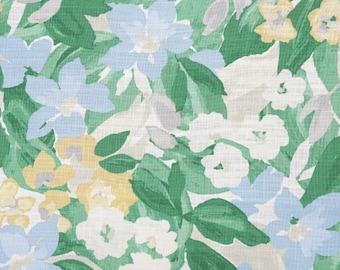 May include: A textile fabric featuring a repeating floral pattern with light blue, pale yellow, and white blossoms set against a backdrop of various shades of green leaves. The material has a visible woven texture with a matte finish throughout.