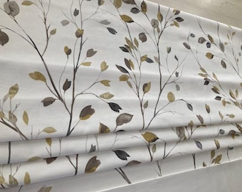 May include: White roman shade with a watercolor-style pattern of brown and yellow leaves and branches.