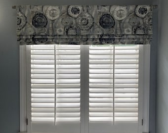 May include: White window shutters with a patterned valance in shades of gray and blue.