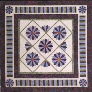 May include: A quilt with a geometric pattern of purple, blue, and green. The center of the quilt features a repeating design of a flower with a starburst pattern. The quilt is surrounded by a border of stripes.