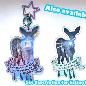 May include: Two iridescent holographic keychains featuring a silhouette of a deer with the text "This action will have consequences" on a banner.