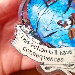 May include: A blue butterfly with a white and blue watercolour design on a clear background. The butterfly is on a banner with the text "This action will have consequences".