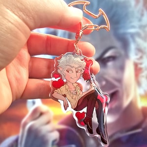 May include: A clear acrylic keychain featuring a cartoon character with white hair, a yellow shirt, and black trousers. The character is holding a red rose and is surrounded by red hearts.