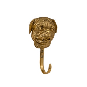 May include: A gold-toned metal hook shaped like a pug dog's head. The hook is attached to a wall with two screws.