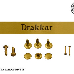 May include: Gold metal plaque with the name "Drakkar" engraved on it. The plaque comes with screws, rivets, and nails for mounting.