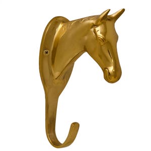May include: A gold-toned metal horse head wall hook. The hook is shaped like a horse's head with a curved hook extending from the bottom.
