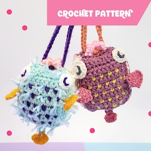 Könnte beinhalten: Zwei gehäkelte Kugelfisch-Anhänger, einer blau und lila, der andere rosa und gelb, mit einer gehäkelten Schnur, die an jedem hängt.