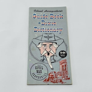 May include: A blue and white guide book titled "Colonel Horsepastures Guide Book & Dixie Dictionary". The cover features a cartoon illustration of a man in a Confederate uniform with a white beard and moustache. The book is priced at 50 cents in "Yankee Money".