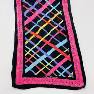 May include: A black silk scarf with a colorful geometric pattern of diagonal stripes in pink, yellow, blue, green, and purple. The scarf has a pink border with a repeating pattern of stylized figures. The text "Creative Memories" is printed in white on the scarf.
