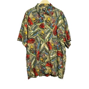 May include: A short-sleeved button-down shirt with a green background and a colorful print of cars, flags, and other designs. The shirt has a collar and a button-up front.