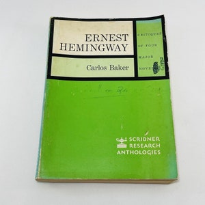 Könnte beinhalten: Ein grün-weißes Buch mit dem Titel "Ernest Hemingway: Kritiken zu vier großen Romanen" von Carlos Baker. Das Buch ist Teil der Scribner Research Anthologies-Reihe.