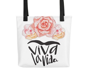 May include: White tote bag with black handles and a floral design. The flowers are pink and yellow watercolor. The text "Viva la Vida" is printed in black below the flowers.