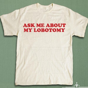 May include: Cream-colored t-shirt with the red text "ASK ME ABOUT MY LOBOTOMY". The shirt is laid flat, showcasing its design. The Legendary Wares logo is visible at the bottom.