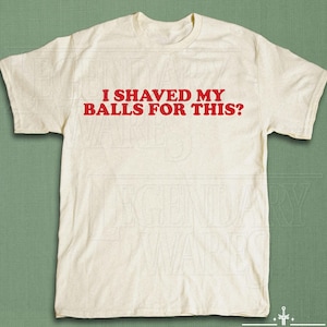 Op de afbeelding: Cr&egrave;mekleurig T-shirt met de rode tekst "I SHAVED MY BALLS FOR THIS?". Het shirt heeft korte mouwen en een ronde hals. Het Legendary Wares-logo staat onderaan.