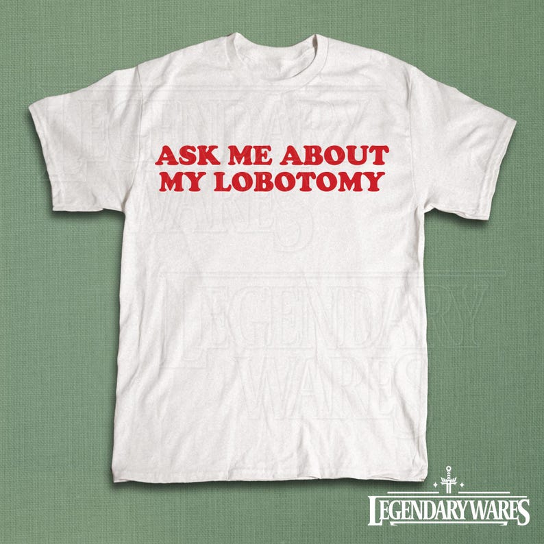 May include: White t-shirt with the red text "ASK ME ABOUT MY LOBOTOMY". The shirt is a crew neck style and appears to be made of cotton. The bottom right corner of the shirt has the text "LEGENDARY WARES" in a stylized font.