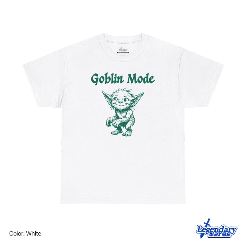 May include: White t-shirt with a green graphic of a goblin and the words "Goblin Mode" above it. The goblin is smiling with pointed ears and a mischievous expression. The shirt is a classic crew neck style.
