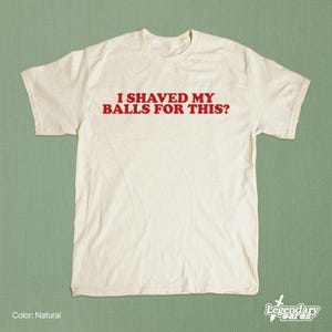 Op de afbeelding: Een cr&egrave;mekleurig T-shirt met de rode tekst "I SHAVED MY BALLS FOR THIS?". Het shirt heeft korte mouwen en een ronde hals. Het Legendary Wares-logo staat rechtsonder.