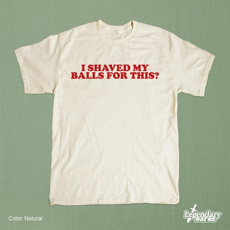 Op de afbeelding: Een cr&egrave;mekleurig T-shirt met de rode tekst "I SHAVED MY BALLS FOR THIS?". Het shirt heeft korte mouwen en een ronde hals. Het Legendary Wares-logo staat rechtsonder.