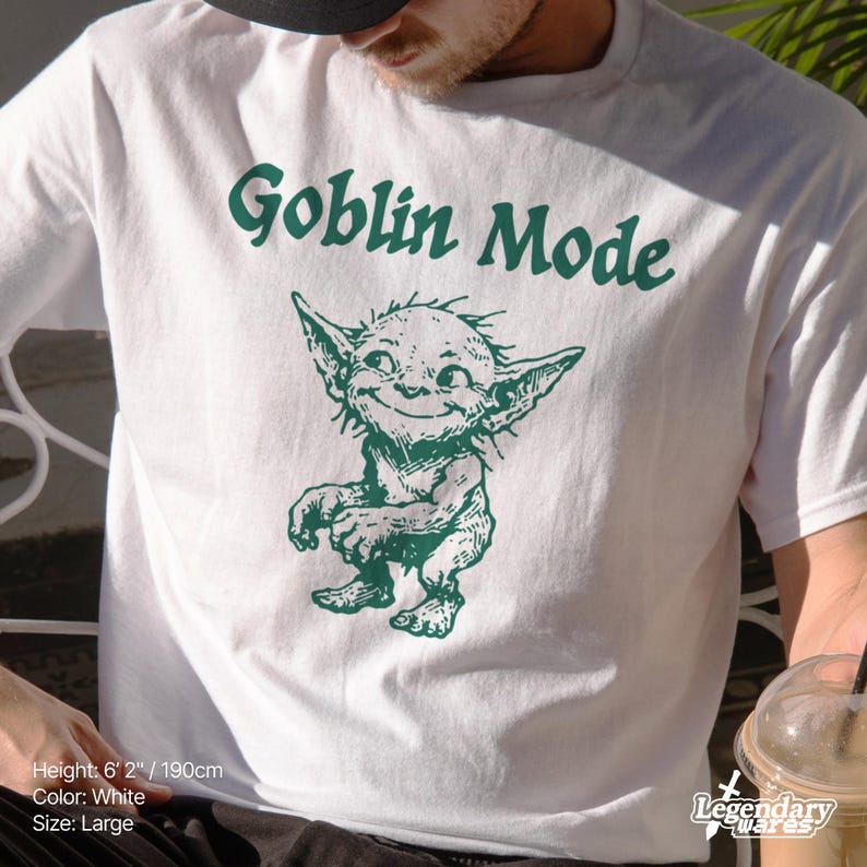 May include: White t-shirt with a green goblin illustration and the words "Goblin Mode". The goblin is smiling. The shirt is size large.