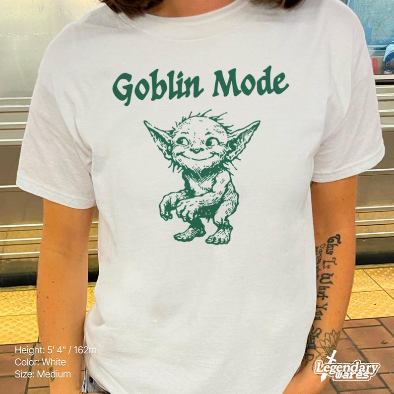 May include: White t-shirt with the text "Goblin Mode" in green above a green cartoon goblin illustration. The shirt is a medium size.