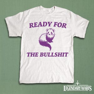 以下が含まれることがあります： 紫色のフェレットのグラフィックと「READY FOR THE BULLSHIT」の文字が入った白いTシャツ。 デザインは様式化されたフェレットのイラストが特徴です。 シャツは柔らかく快適な素材で作られています。