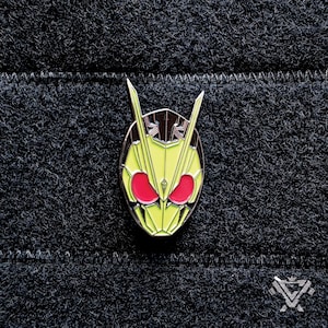 Op de afbeelding: Een gele en zwarte emaille pin met een gestileerd gezicht met rode ogen. De pin is een populair personage uit een Japanse tv-show.