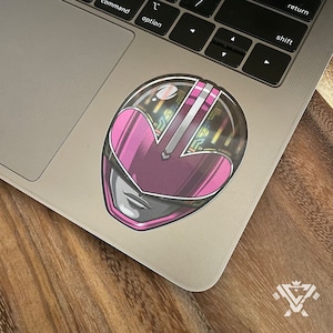May include: Pink Power Ranger helmet sticker with a detailed design and a metallic finish.