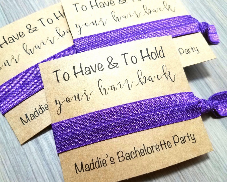 May include: Purple hair ties with brown cardstock tags that read "To Have & To Hold your hair back" and "Maddie's Bachelorette Party".